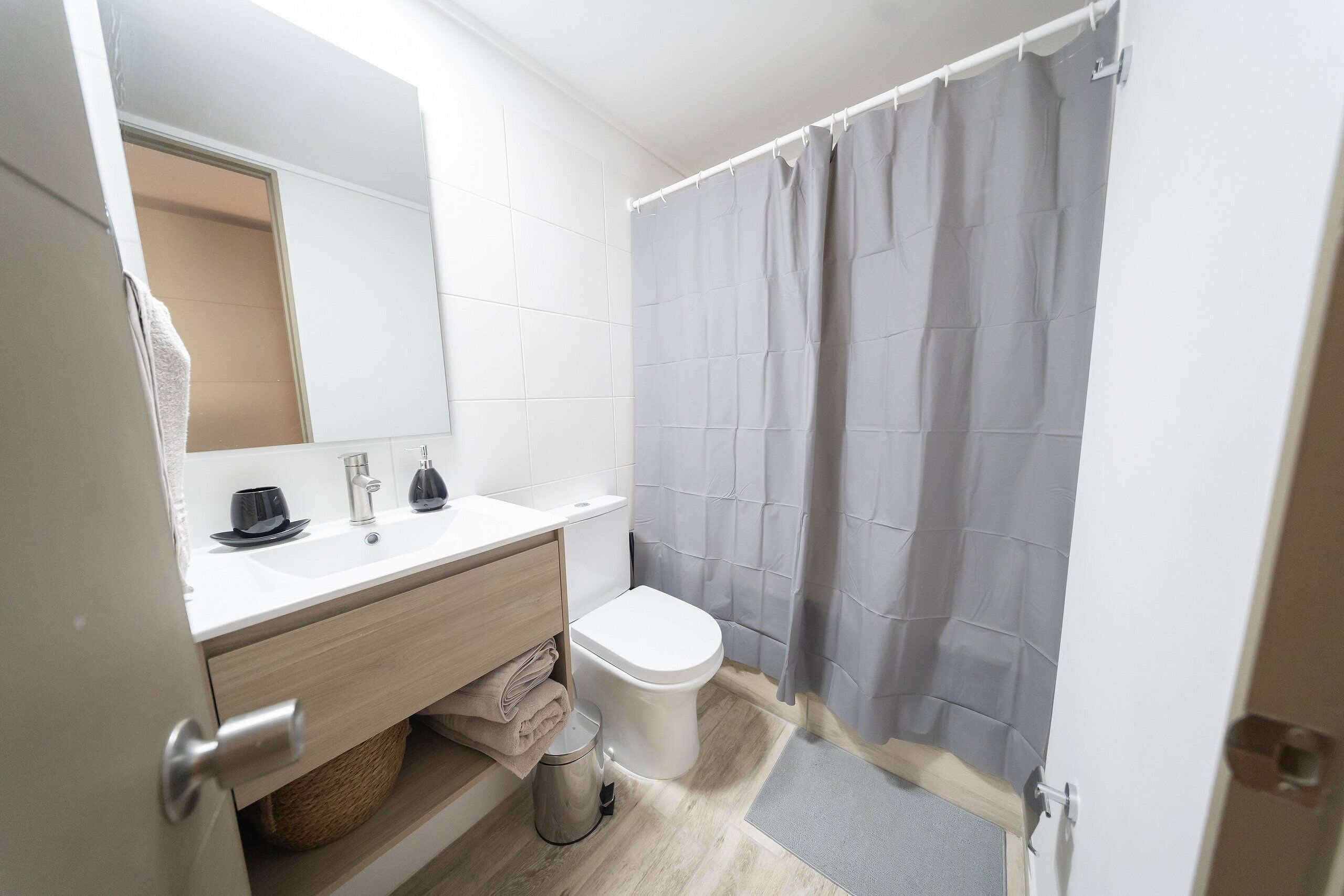 Een moderne badkamer met een witte wastafel, spiegel en toilet.