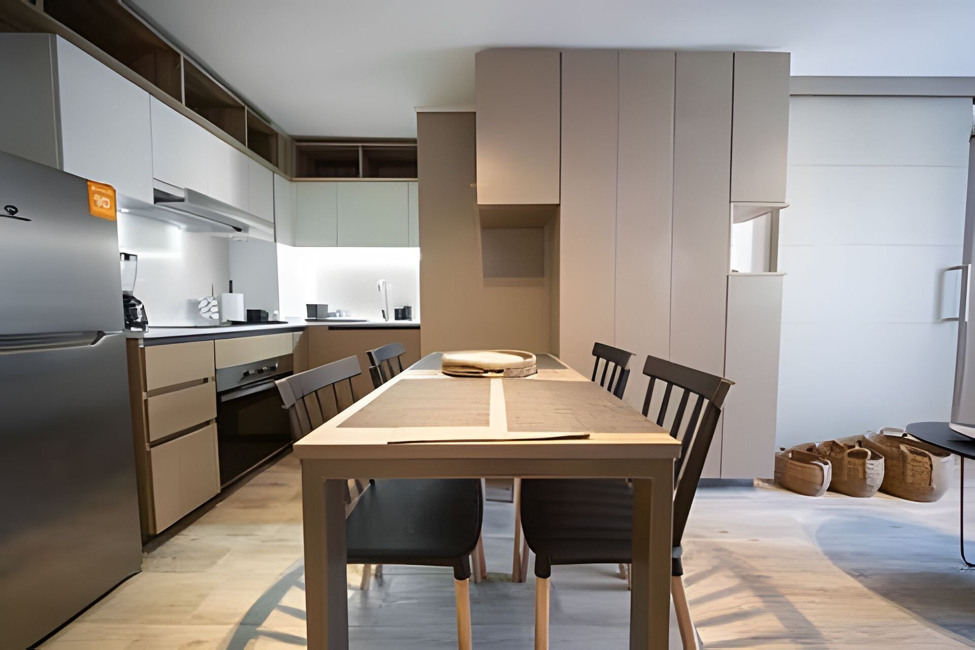 A modern kitchen with a central island, built-in appliances, and a dining area with a table and chairs.