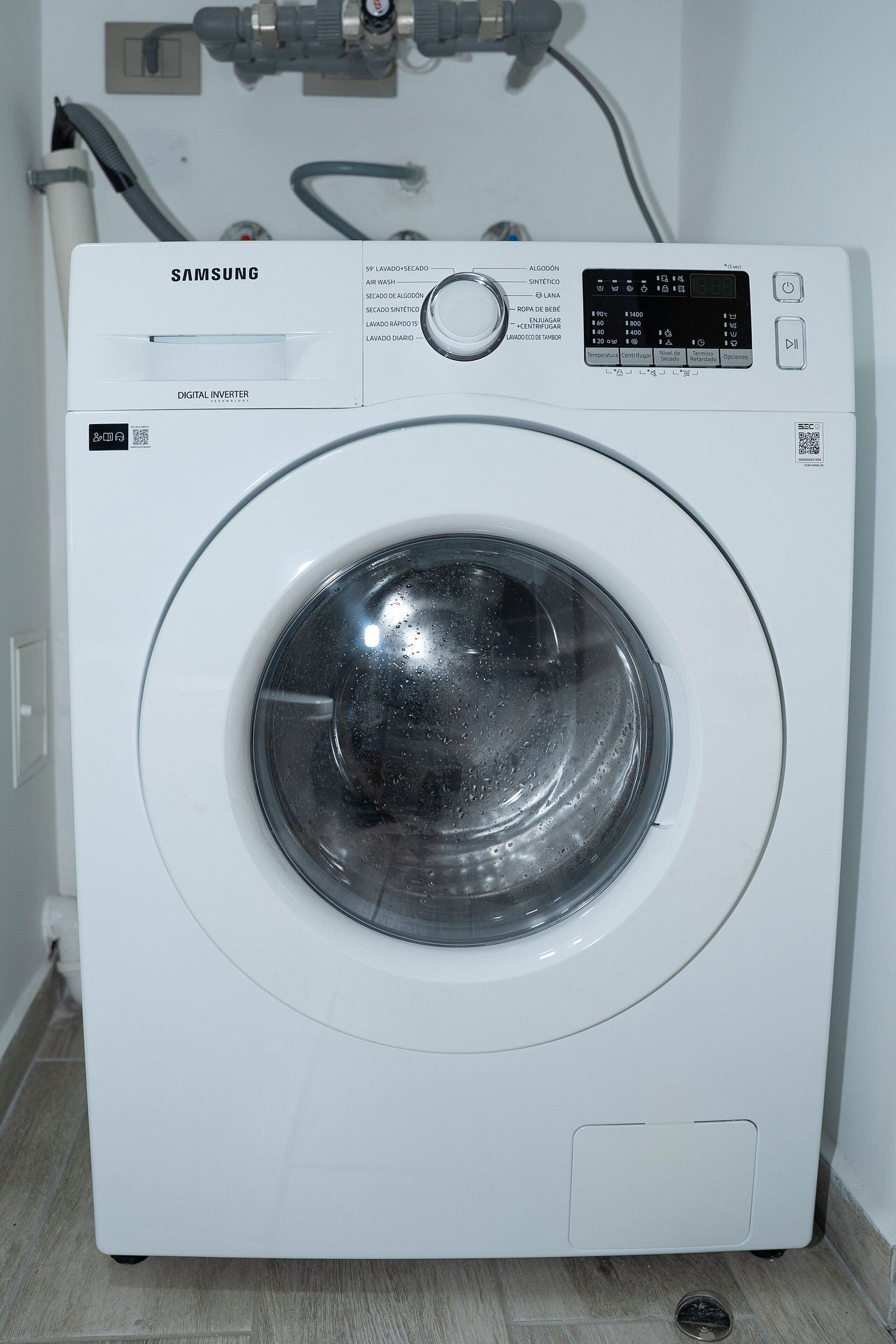 A Samsung digital inverter washing machine with a control panel, water inlet, and drainage hose.