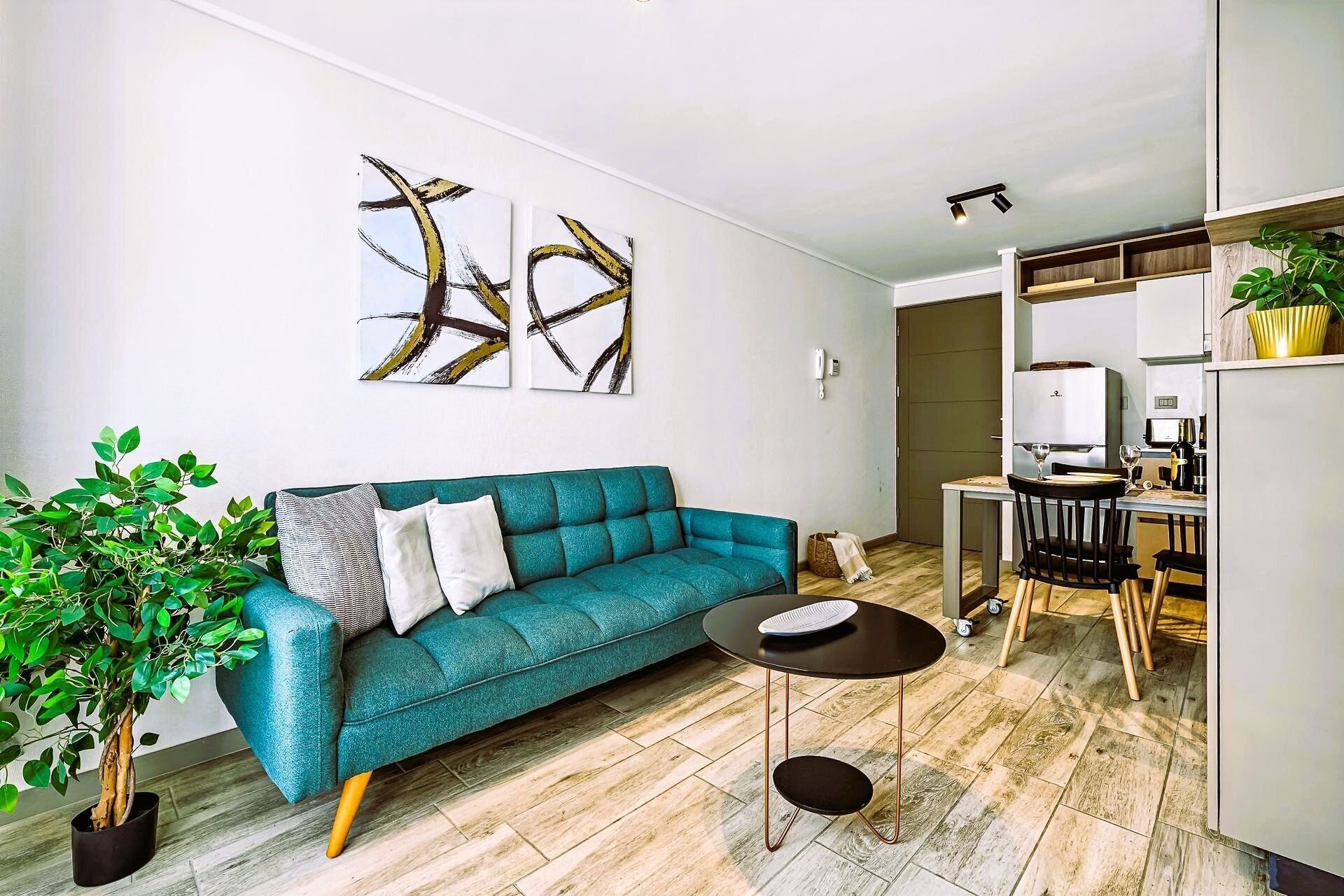 Una sala moderna con un sofá azul turquesa, una mesita redonda y arte abstracto en la pared.
