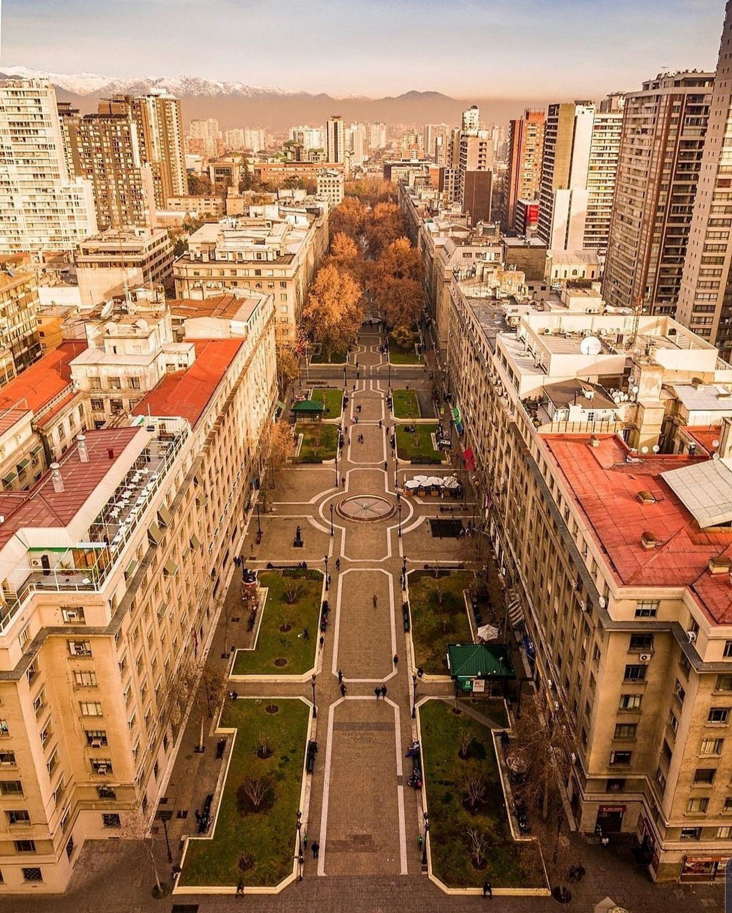 An aerial view of a cityscape with a central square surrounded by high-rise buildings.