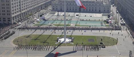 A flagpole with a flag, surrounded by a large crowd and a ceremonial formation.