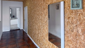 Ein Korridor mit Holzwandverkleidung, Fliesenboden und einer sichtbaren Tür zu einem Schlafzimmer.