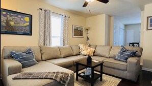 A living room with a sectional sofa, a coffee table, and a ceiling fan. - A 3-Bedroom Cozy Cottage - 2 Blocks from the River (Colonial Beach)