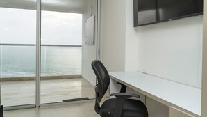 A modern office with a large window overlooking the sea, a white desk, and a black office chair. - Loft Apartment 1510 (Cartagena de Indias)