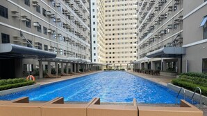 Une piscine entourée d’immeubles résidentiels de grande hauteur, dotés de balcons et de climatiseurs.