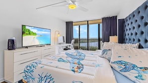 A hotel room with a bed, a desk, a television, and a view of the outdoors.