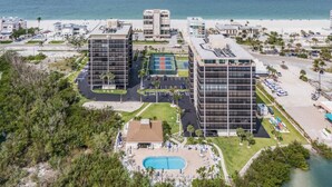 A beachfront hotel with multiple high-rise buildings, a swimming pool, and a beach area.