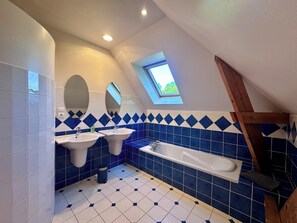 Ein Badezimmer mit zwei Waschbecken, einer Badewanne und einem Oberlicht.
