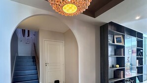 Un interior moderno con una escalera, una puerta blanca y una estantería oscura.