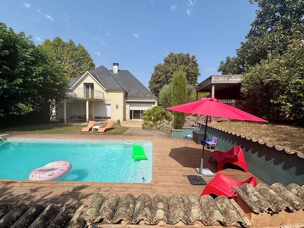 Ein Garten mit Pool, Liegestühlen und einer Holzterrasse.