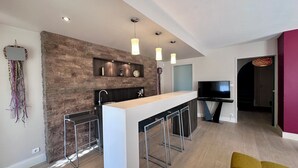 Una cocina moderna con protector de piedra, taburetes de bar e iluminación colgante.