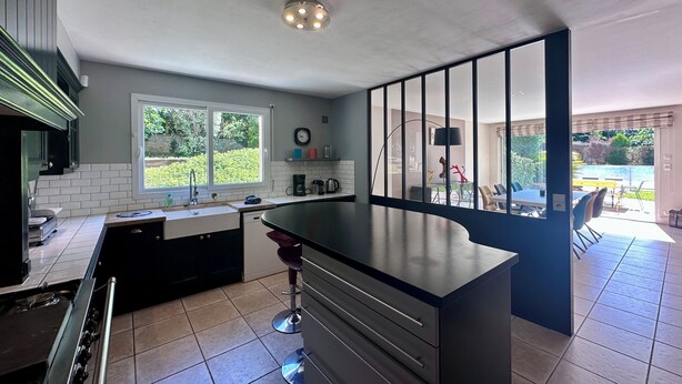 Una cocina moderna con una isla central, un comedor con vistas y un gran ventanal.