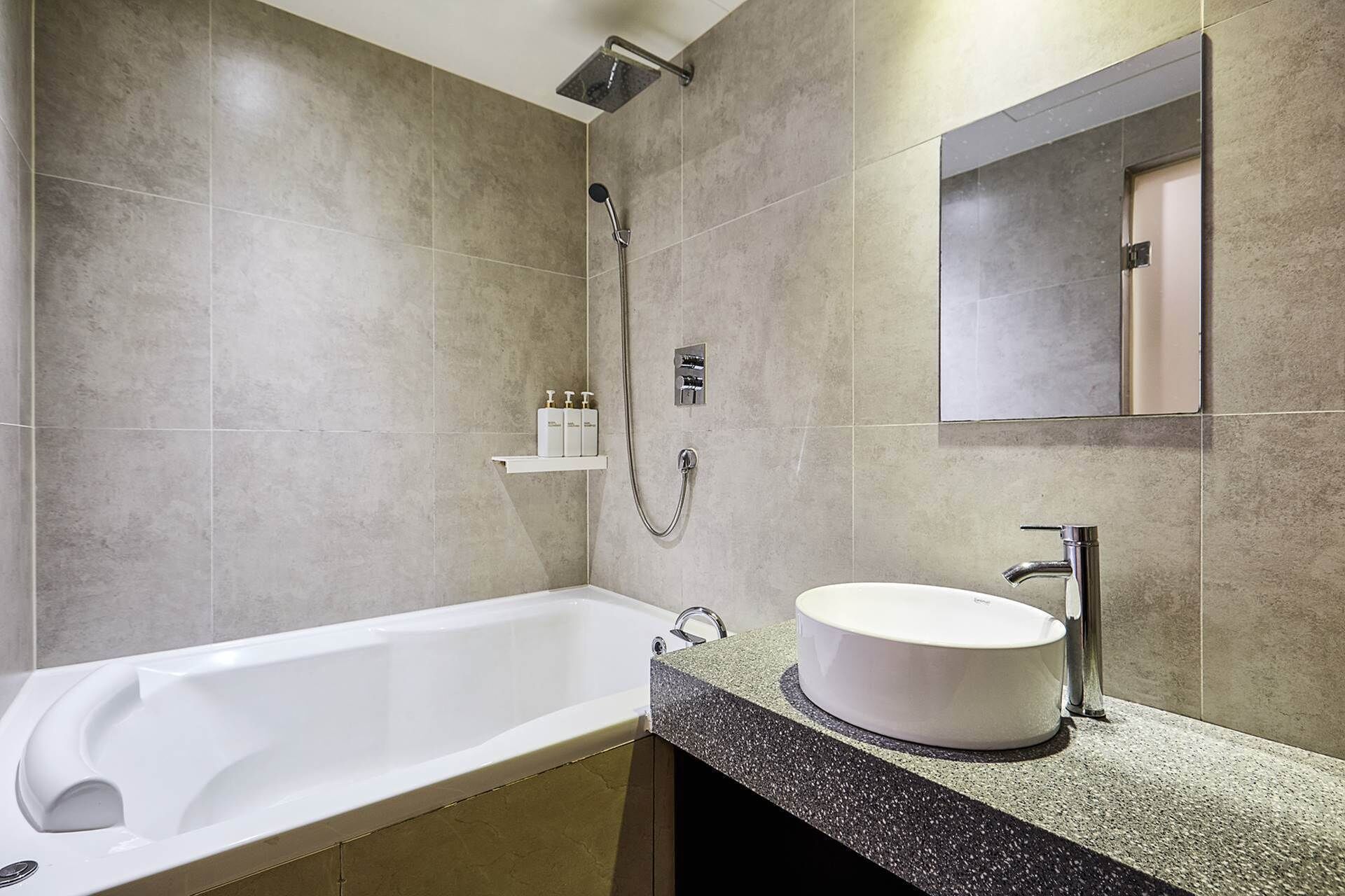 Een moderne badkamer met een vrijstaand bad, een rond wastafel en een handdouche.