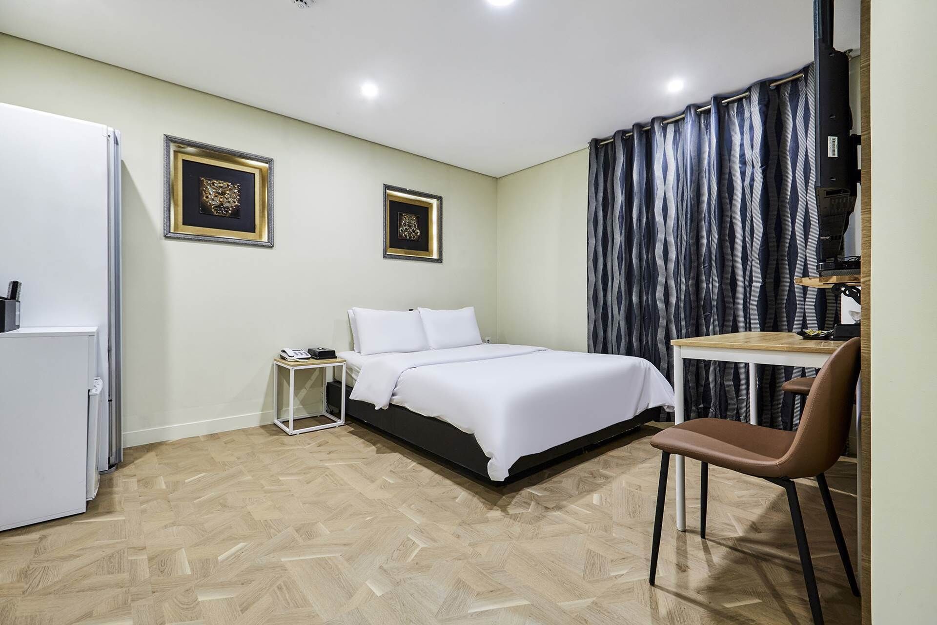 Una camera da letto con un letto, una scrivania, una sedia e due quadri appesi al muro.