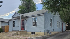 A two-story house with a red front door, a small front porch, and a driveway leading to the street. - Cozy Retreat Near Pikes Peak & Downtown (Colorado Springs)