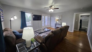 A living room with a brown leather sofa, a glass coffee table, a lamp, and a ceiling fan. - Cozy Retreat Near Pikes Peak & Downtown (Colorado Springs)