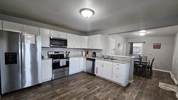 A modern kitchen with stainless steel appliances, white cabinetry, and a wooden floor. - Cozy Retreat Near Pikes Peak & Downtown (Colorado Springs)