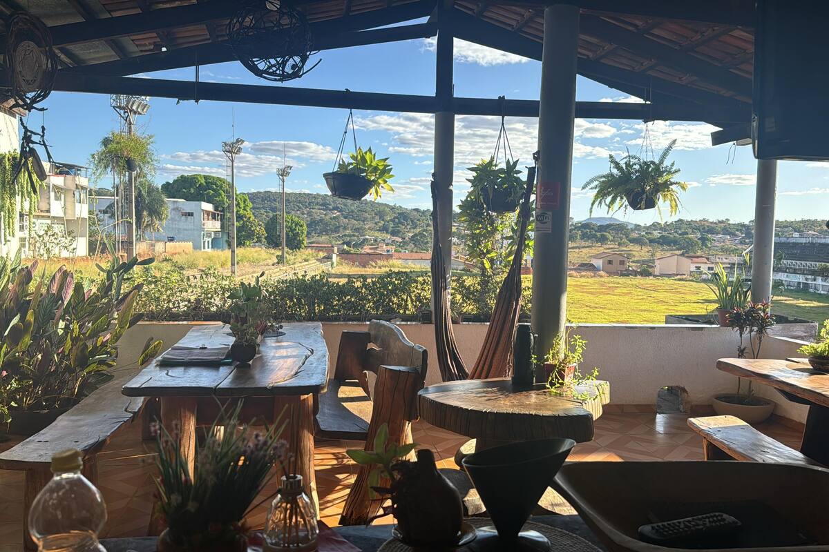 A covered outdoor seating area with a view of a rural landscape, including fields and distant buildings.