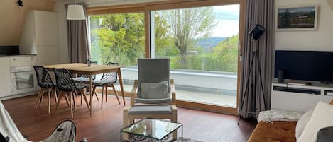 A modern living room with a sofa, a glass coffee table, and a dining area with chairs and a table.