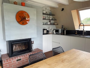 A kitchen with a fireplace, a dining table, and a window. - Beautiful holiday home surrounded by nature (Les Enfers)