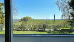 A room with a large window offering a view of a green field and trees. - Beautiful holiday home surrounded by nature (Les Enfers)