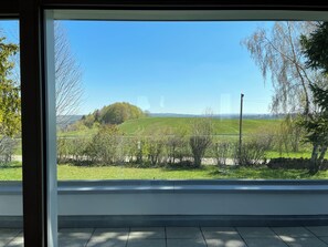 A room with a large window offering a view of a green field and trees. - Beautiful holiday home surrounded by nature (Les Enfers)