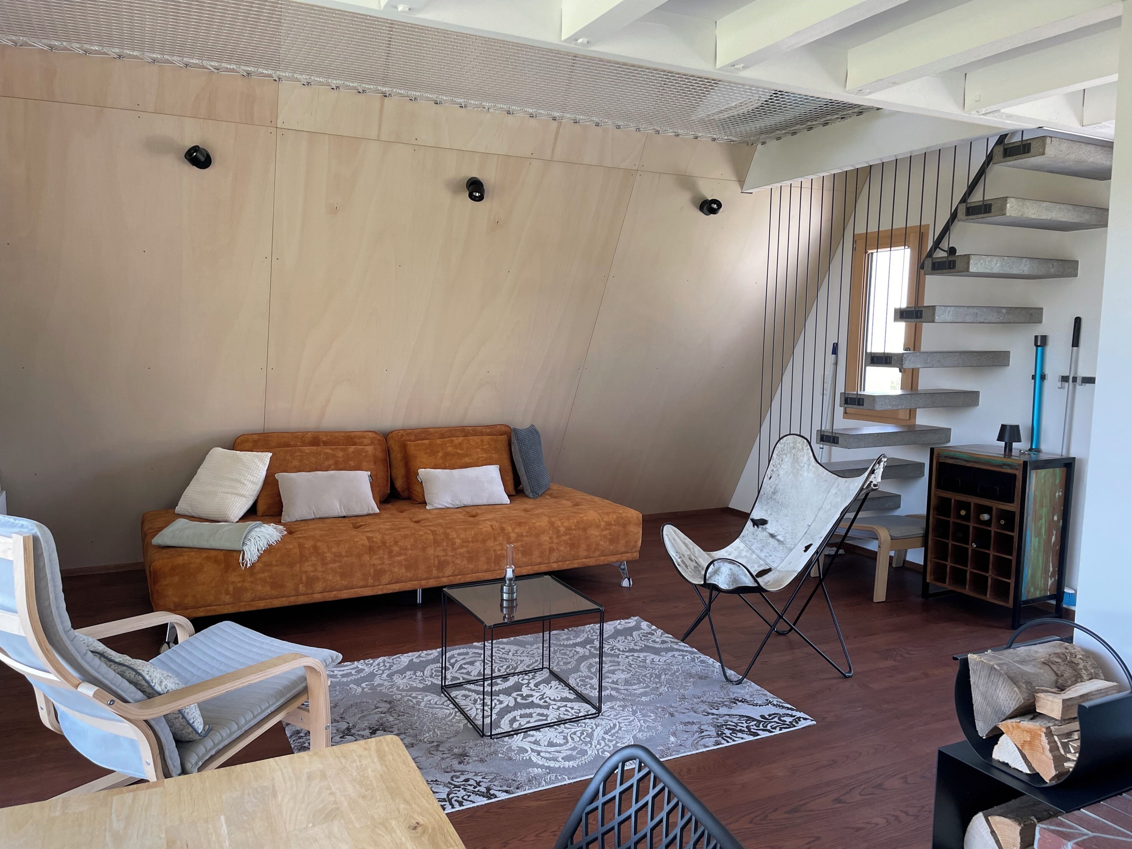 Ein modernes Wohnzimmer mit einer Couch, Sesseln, einem Couchtisch und einer Treppe.
