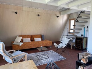 A modern living room with a sofa, chairs, a coffee table, and a staircase. - Beautiful holiday home surrounded by nature (Les Enfers)