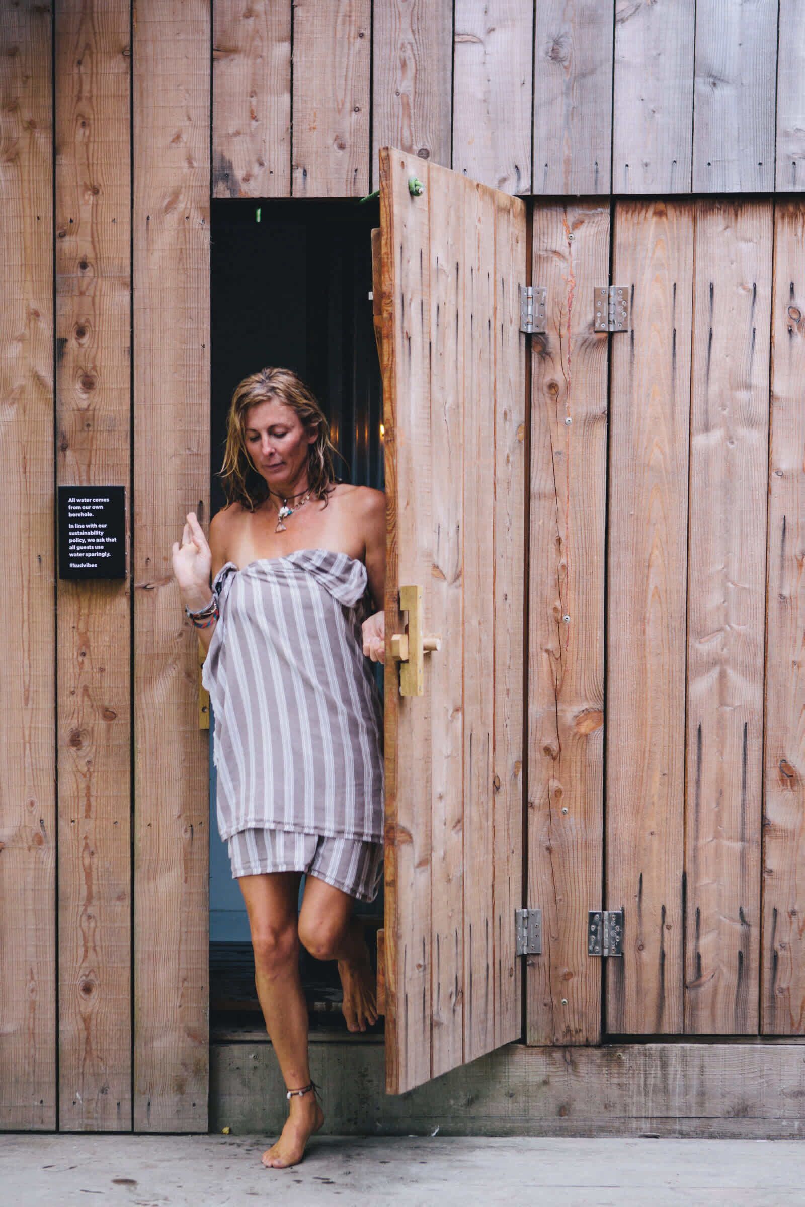A wooden door with a sign stating "All water comes from our well with our sustainability and water conservation."