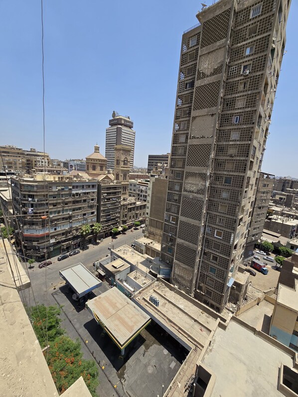 A high-rise building with a grid-like facade, surrounded by other buildings and a clear sky.