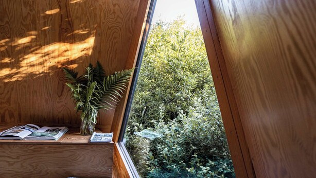 A wooden interior with a window overlooking a garden.