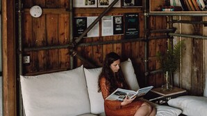 A cozy room with wooden walls, a white sofa, and a bookshelf.