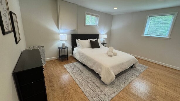 Une chambre à coucher avec un lit, deux tables de chevet, une commode noire et un tapis à motifs.