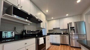 Une cuisine moderne avec des meubles blancs, des appareils en acier inoxydable et un plancher en bois.