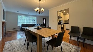 Un salon moderne avec une table à manger en bois, des chaises foncées et un lustre.