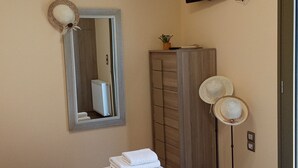A hotel room with a bed, a mirror, a wardrobe, a television, and a standing fan. - Villa Kastania, Melidoni, Chania, Crete. (Melidoni Chania)