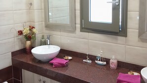 A bathroom with a white sink, a mirror, a window, and a vanity with a brown countertop. - Villa Kastania, Melidoni, Chania, Crete. (Melidoni Chania)