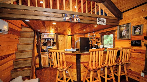 Interior de madera con una zona de bar, sillas de madera, un refrigerador y un letrero que indica que se admiten perros.