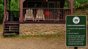 A cabin with a stone foundation, a porch with chairs, and a sign listing check-in requirements. - Codex Cabin (Murfreesboro)