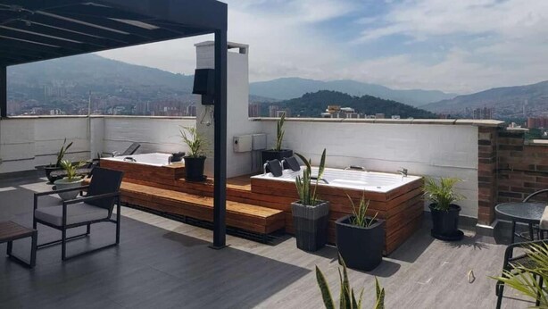 Terraza en la azotea con piso de madera, zona de estar y tinaco.
