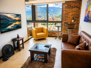 A modern living room with a large window, a sofa, a coffee table, and a TV. - penthouse jacuzzi rooftop fun in the sun (Medellín)