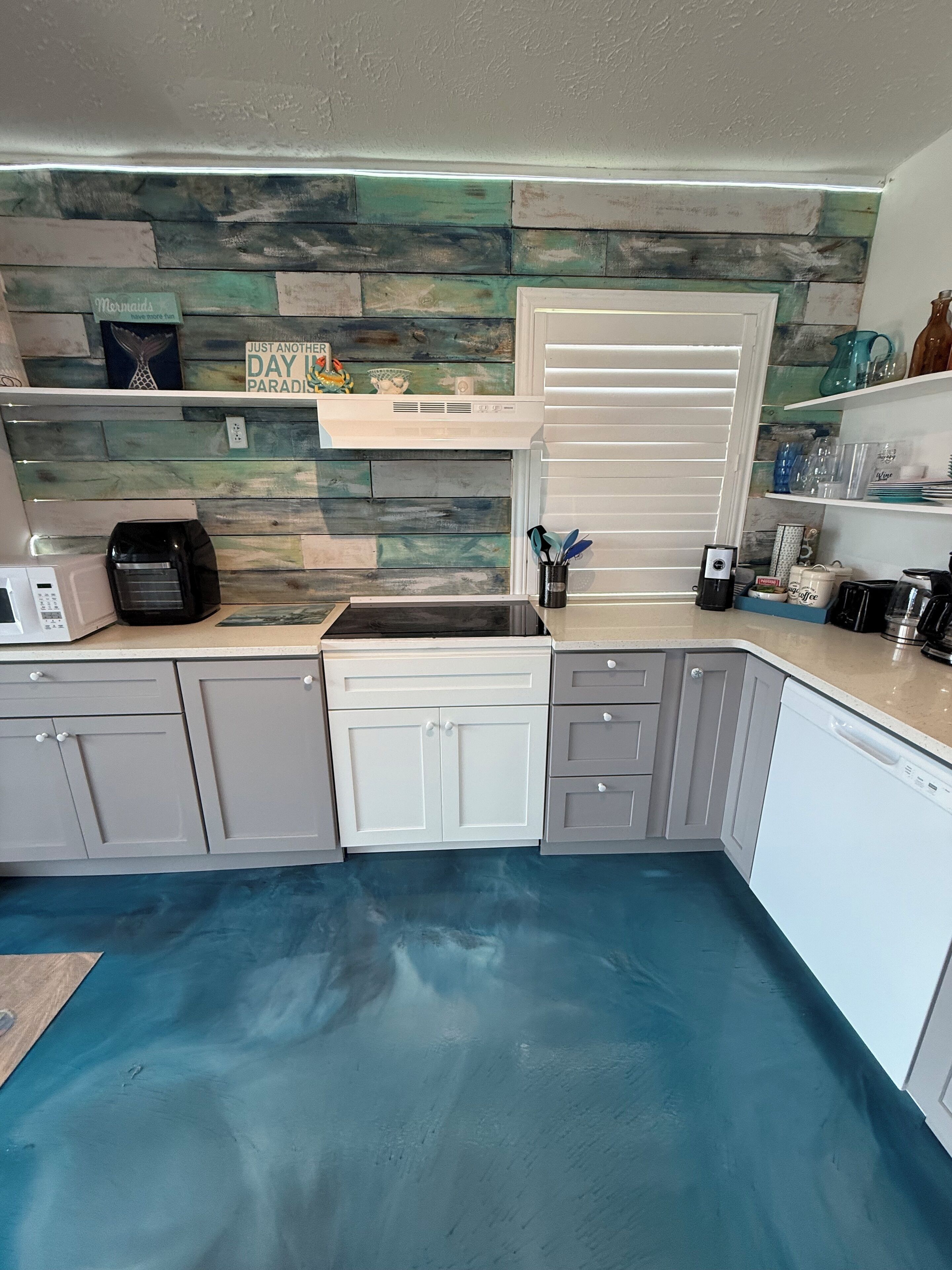 A modern kitchen with grey cabinets, a built-in microwave, and a coffee maker.