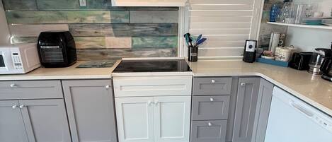 A modern kitchen with grey cabinets, a built-in microwave, and a coffee maker.