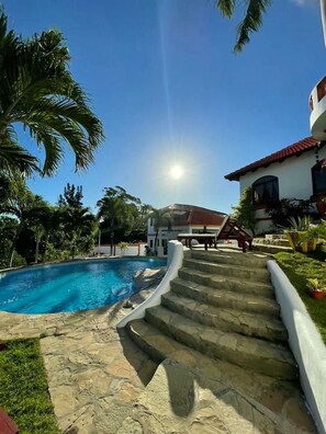 Una piscina con escalones de piedra que conducen a una casa de techo rojo.
