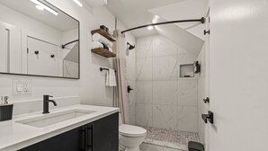 A modern bathroom with a white vanity, a black sink, a toilet, and a shower area with a curved glass door. - Sleeps 4 Walk to Liberty Bell Heart of Old City (Philadelphia)