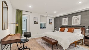 A modern bedroom with a large bed, a desk, and a chair. There are framed pictures on the wall and a window with curtains. - Sleeps 4 Walk to Liberty Bell Heart of Old City (Philadelphia)