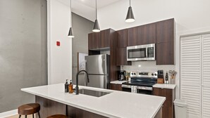 A modern kitchen with a central island, stainless steel appliances, and dark wood cabinets. - Sleeps 4 Walk to Liberty Bell Heart of Old City (Philadelphia)