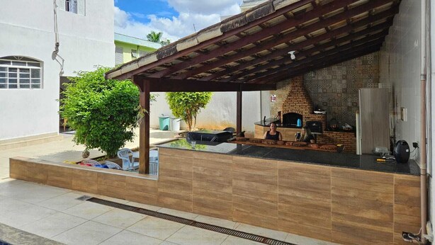 Un patio con horno de ladrillo, mobiliario exterior y una pérgola.