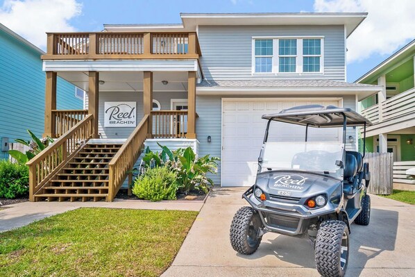 Une maison à deux étages avec un porche couvert et un véhicule de golf garé devant.
